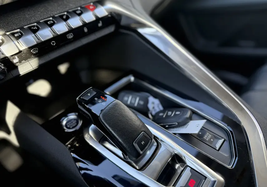 Gros plan sur la console centrale intérieure du Peugeot 5008 gris, mettant en valeur le levier de vitesses automatique et les commandes.
