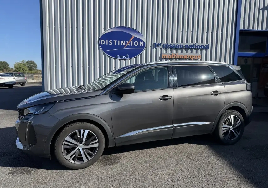 Peugeot 5008 gris vue de profil côté gauche, stationnée devant un bâtiment avec enseigne Distinxion.