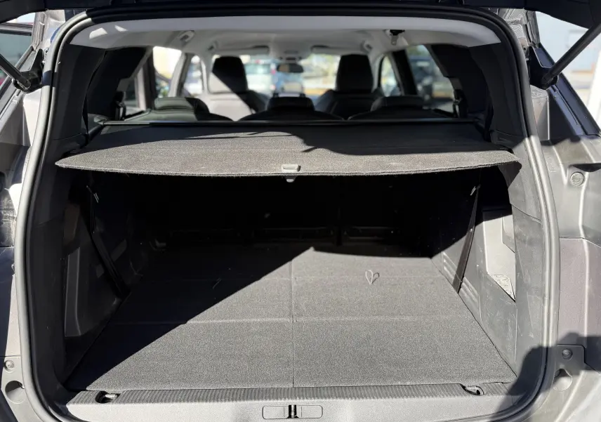 Coffre ouvert vu de l'arrière d'un Peugeot 5008 gris 2021, avec cache-bagages déployé et sièges arrière visibles.