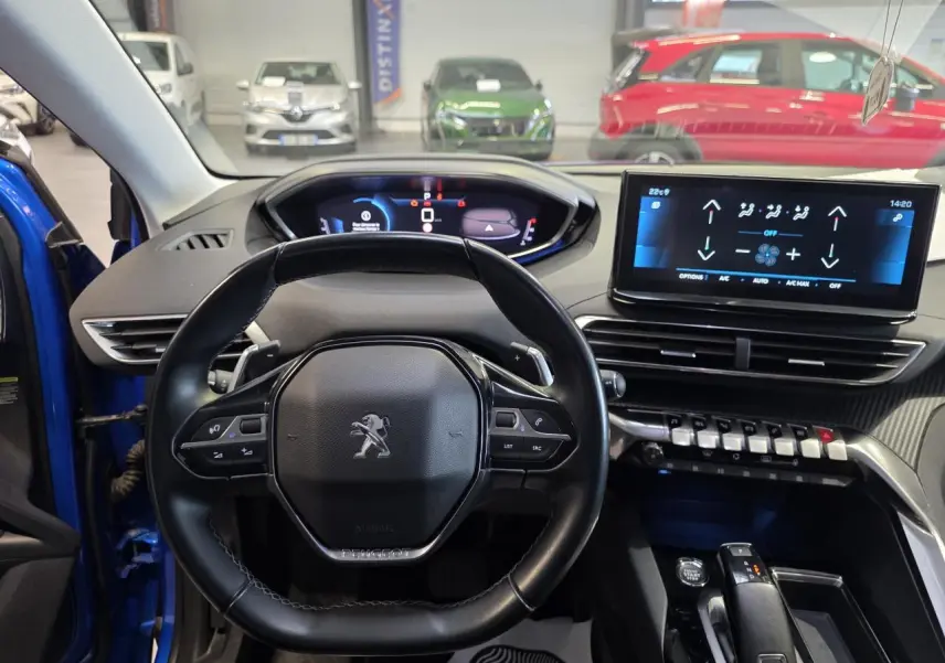 Vue intérieure centrée sur le volant cuir noir et le tableau de bord numérique du Peugeot 3008 Bleu Iron 2022.