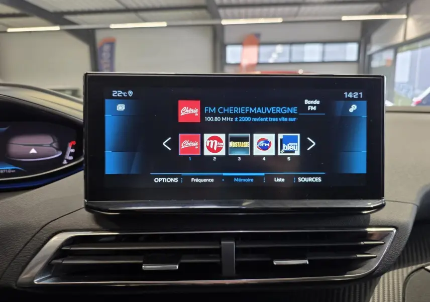 Écran tactile central du Peugeot 3008 2022 affichant la radio FM dans un intérieur avec décors carbone.