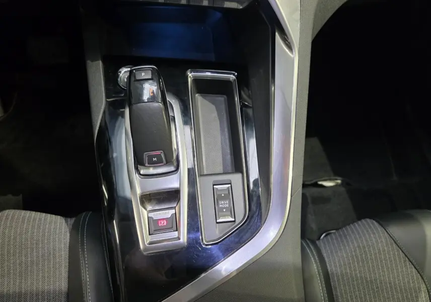 Gros plan sur la console centrale noire brillante du Peugeot 3008 avec levier de vitesse automatique et bouton Drive Mode.