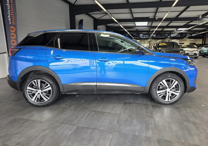 Profil droit d'un Peugeot 3008 bleu Iron métallisé avec jantes alliage bi-ton et vitres surteintées en intérieur showroom.