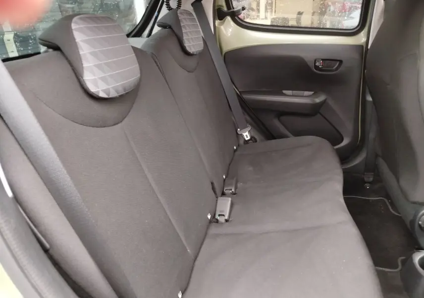 Vue intérieure côté conducteur du Peugeot 108 2021 avec volant cuir, tableau de bord noir et sièges tissu gris à motifs.