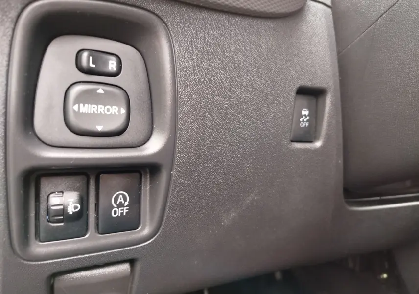 Gros plan sur les commandes de réglage des rétroviseurs et des fonctions d'assistance côté conducteur d'une Peugeot 108 2021.