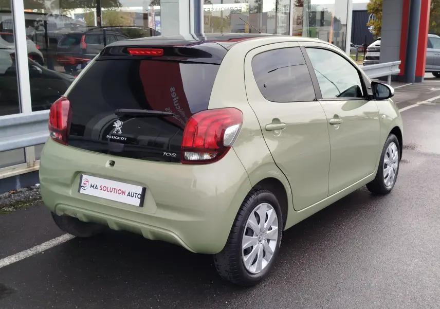Vue 3/4 arrière droite d'une Peugeot 108 Smooth Green 2021 avec vitre arrière noire et feux arrière rouges.