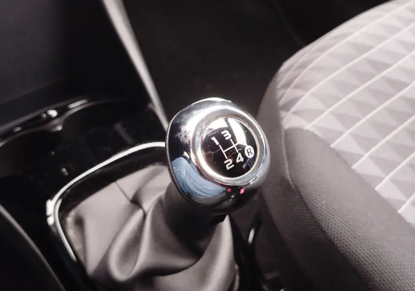Gros plan sur le rétroviseur chromé côté gauche d'une Peugeot 108 Smooth Green avec badge Style sous la pluie.