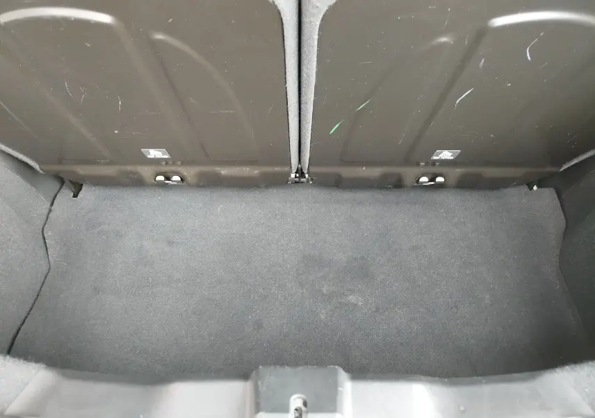 Coffre arrière ouvert vu de dessus, intérieur en tissu gris foncé, sans chargement visible.