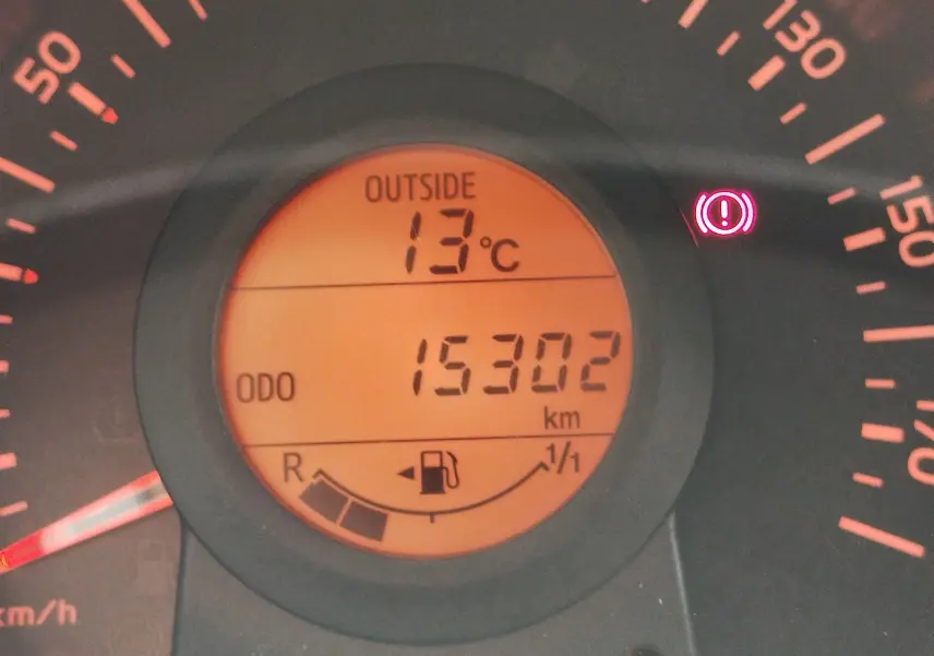 Gros plan sur l'affichage du tableau de bord orange du Peugeot 108, indiquant 15 302 km et une température extérieure de 13°C.
