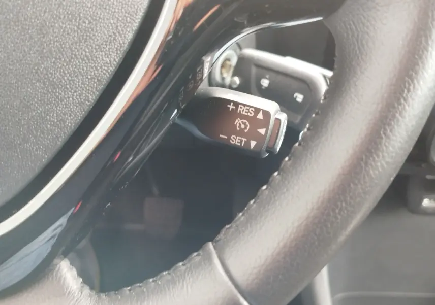 Gros plan sur le levier de régulateur de vitesse derrière le volant en cuir noir du Peugeot 108 2021.