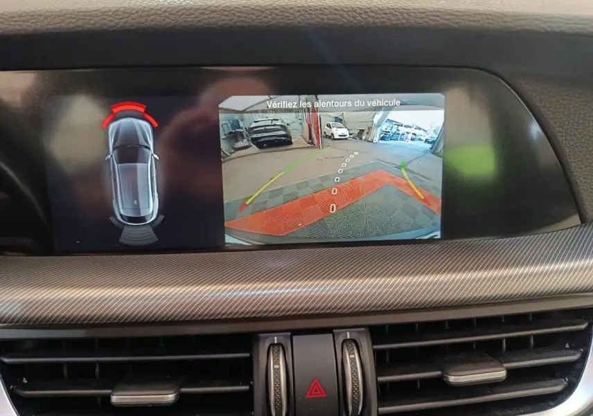 Écran tactile central affichant la caméra de recul et les capteurs de stationnement de l'Alfa Romeo Stelvio gris foncé.