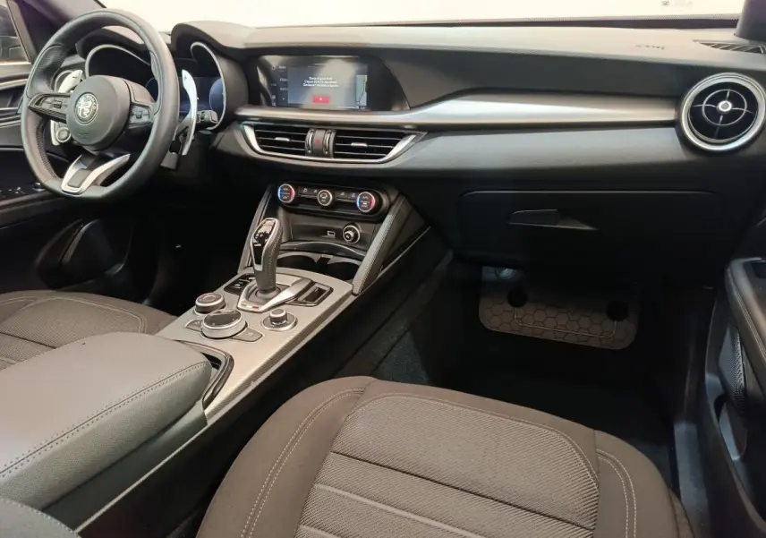 Intérieur noir de l'Alfa Romeo Stelvio 2024, vue côté passager avec console centrale et écran tactile visible.