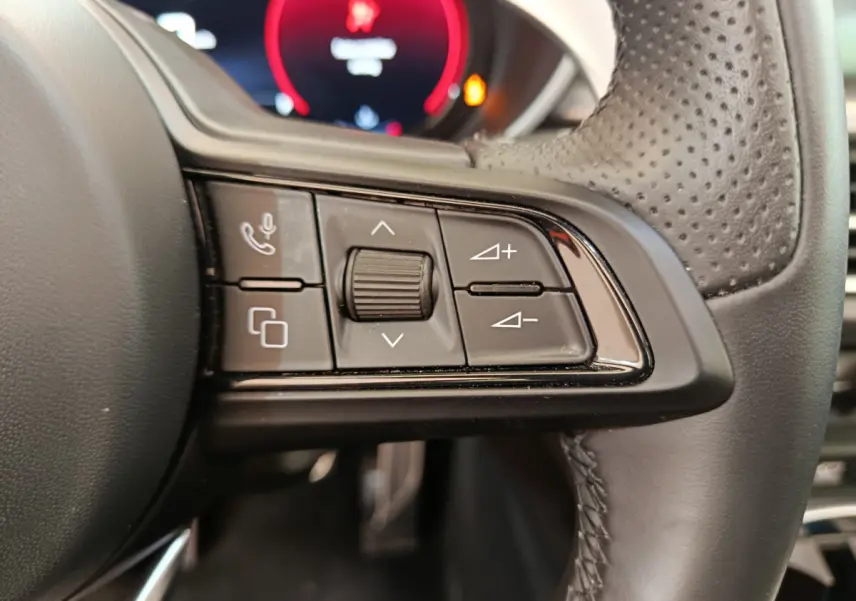 Gros plan sur les commandes multifonctions à droite du volant en cuir perforé de l'Alfa Romeo Stelvio gris foncé 2024.