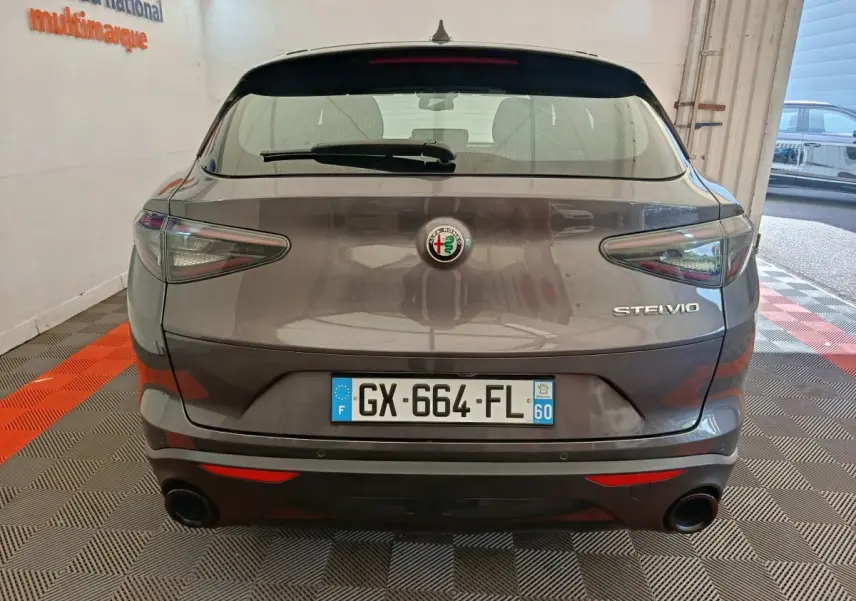 Vue arrière d'un Alfa Romeo Stelvio gris foncé 2024 avec feux LED et double sortie d'échappement ronde.