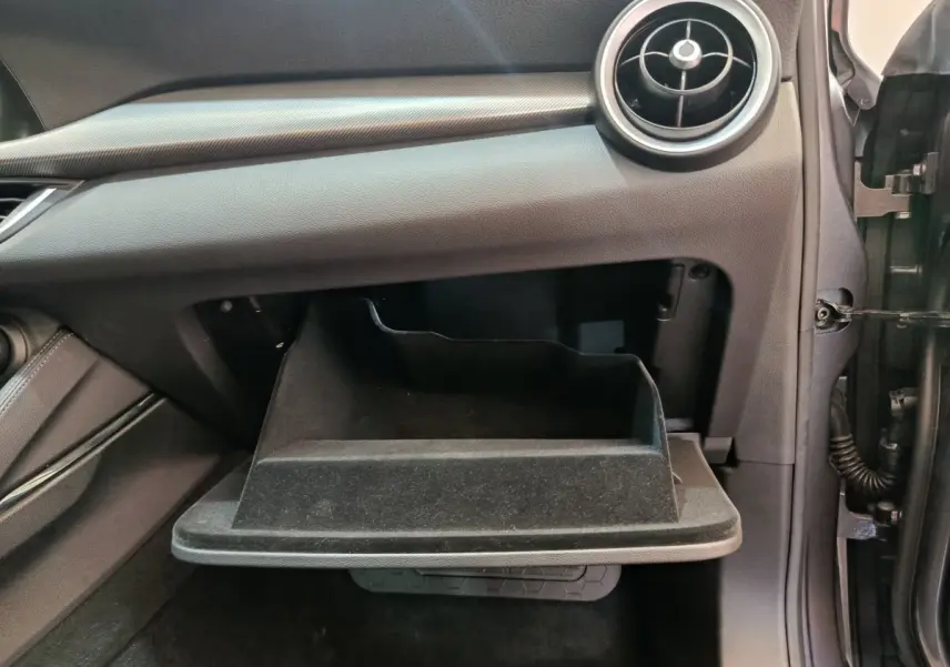 Gant de rangement ouvert côté passager de l'Alfa Romeo Stelvio gris foncé, montrant la texture intérieure noire.