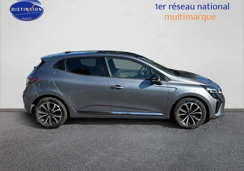 Profil droit d'une Renault Clio V gris pizzara avec jantes alliage noires et calandre chromée visible sur fond clair.