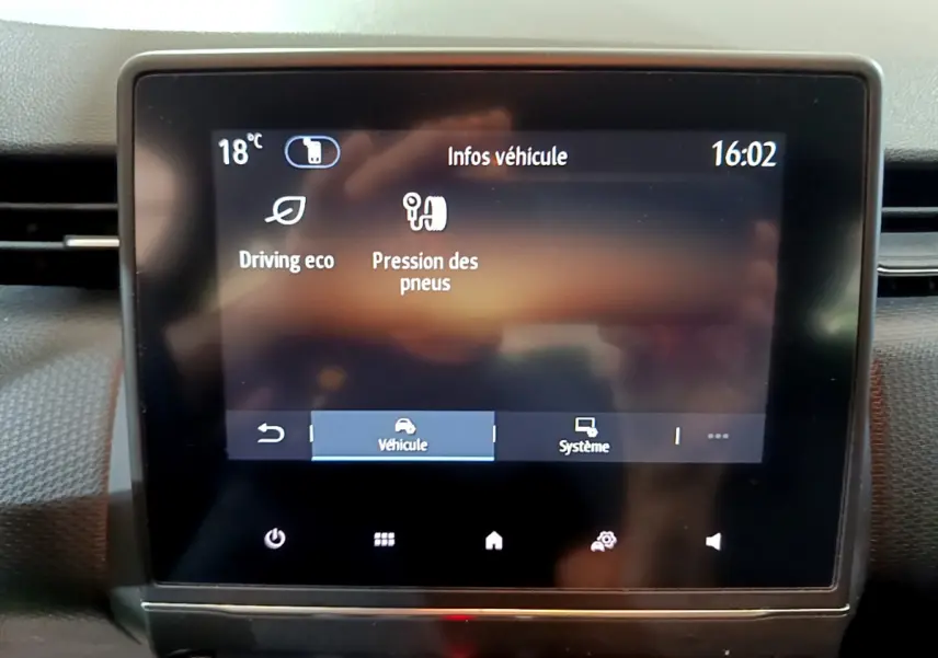 Écran tactile central affichant les infos véhicule dans l'habitacle d'une Renault Clio Business blanc, vue frontale rapprochée.