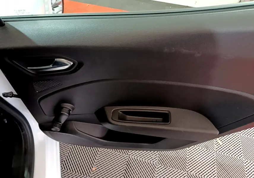 Intérieur de la porte côté gauche d'une Renault Clio Business TCe 90 blanche, avec poignée et commande de vitre manuelle.