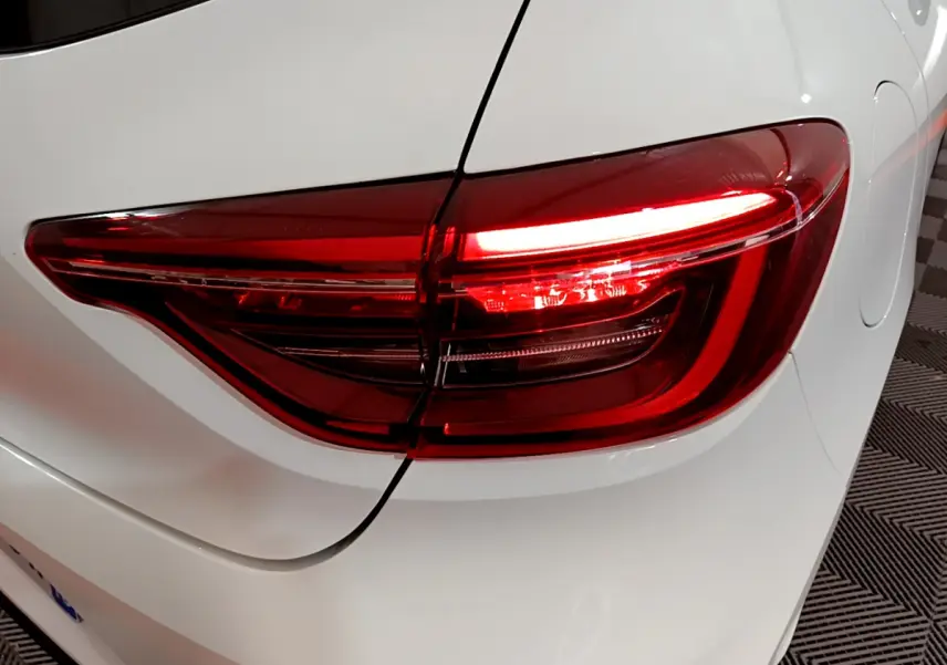 Feu arrière droit allumé de la Renault Clio Business TCe 90 blanche, vue rapprochée sur l'arrière du véhicule.