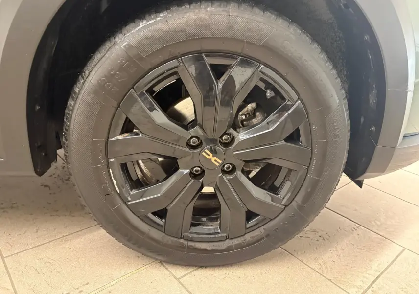 Gros plan sur la roue avant gauche avec jante noire brillante du Dacia Sandero Stepway Vert Cèdre 2023.