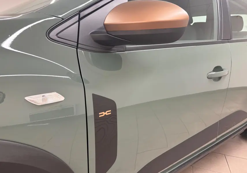 Vue latérale côté gauche du Dacia Sandero Stepway 2023 en vert cèdre, avec rétroviseur bronze et logo Stepway sur la porte.