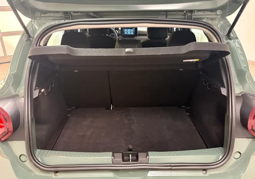 Coffre ouvert vu de l'arrière d'une Dacia Sandero Stepway 2023 vert cèdre avec tablette de coffre relevée.