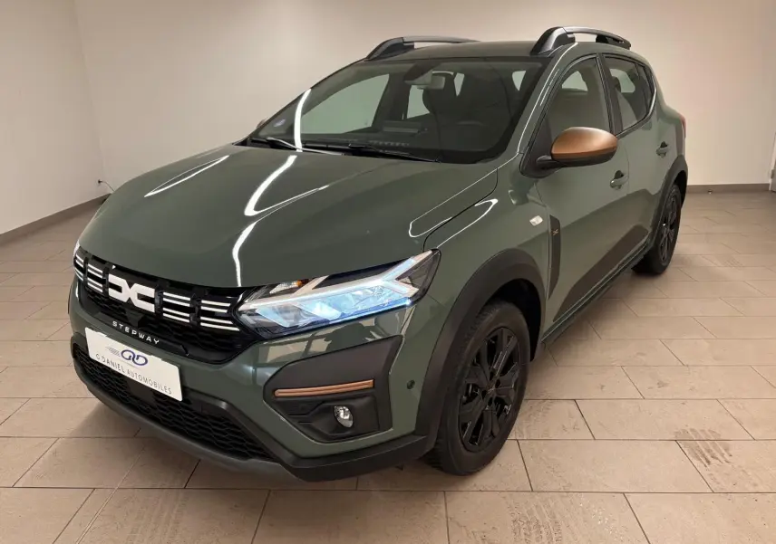 Vue 3/4 avant droite d'une Dacia Sandero Stepway 2023 vert cèdre avec rétroviseurs bronze et jantes noires.