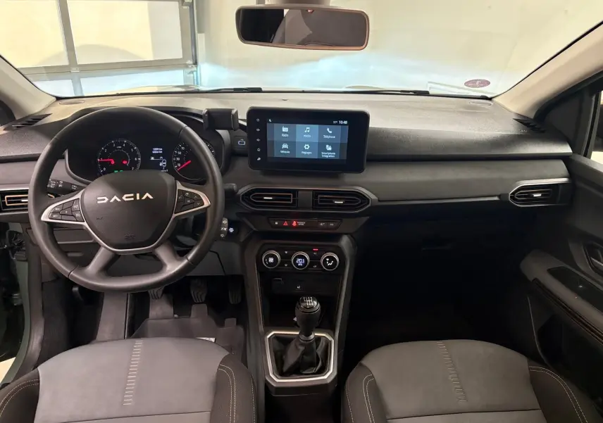 Vue intérieure avant du tableau de bord et volant de la Dacia Sandero Stepway 2023 avec boîte manuelle et écran tactile central.