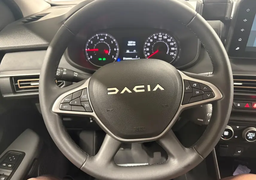 Vue rapprochée du volant noir de la Dacia Sandero Stepway 2023 avec tableau de bord et commandes au volant visibles.