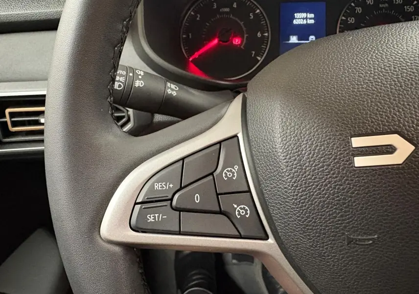 Gros plan sur le volant du Dacia Sandero Stepway 2023, montrant les commandes de régulateur de vitesse et le tableau de bord.