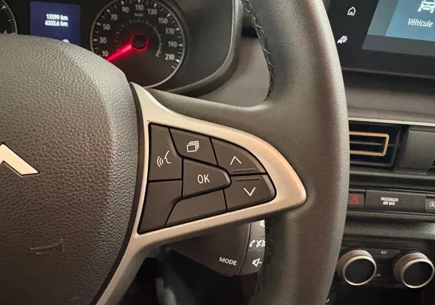 Gros plan sur le volant et le tableau de bord d'une Dacia Sandero Stepway 2023, détails des commandes au volant visibles.