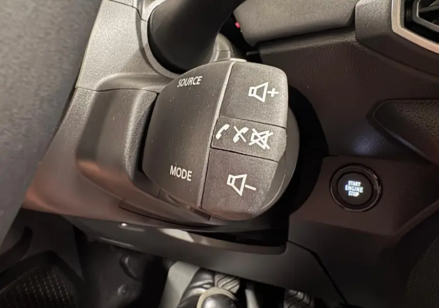 Gros plan sur la commande au volant et le bouton start/stop du tableau de bord du Dacia Sandero Stepway 2023.