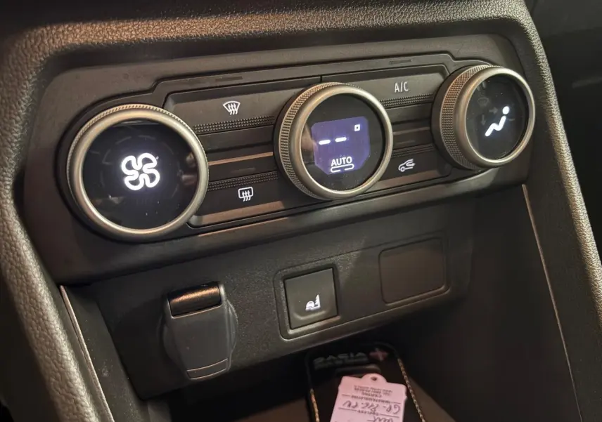 Gros plan sur les commandes de climatisation et siège chauffant du tableau de bord du Dacia Sandero Stepway 2023.