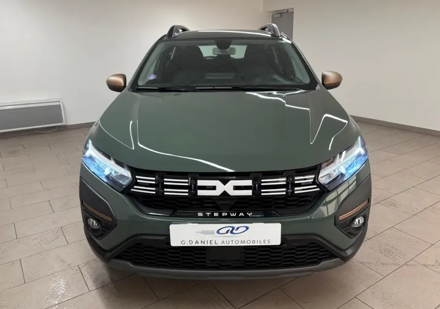 Vue frontale d'une Dacia Sandero Stepway 2023 en vert cèdre avec détails bronze sur les rétroviseurs et calandre distinctive.