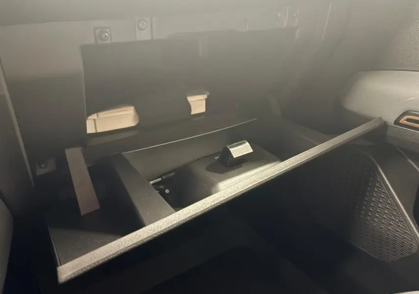Intérieur du coffre à gants ouvert du Dacia Sandero Stepway 2023, montrant un rangement compartimenté en plastique noir.