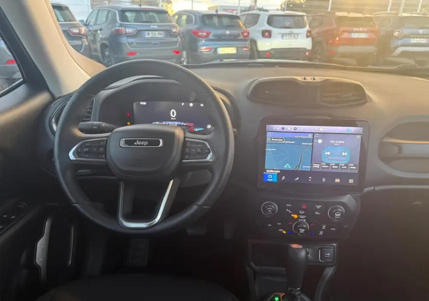 Vue intérieure du poste de conduite du Jeep Renegade 2024, volant noir et écran tactile avec GPS allumé.