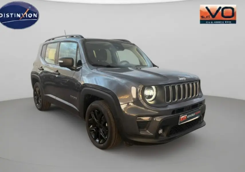 Jeep Renegade gris anthracite en 3/4 avant droit avec jantes alliage noires et barres de toit visibles.