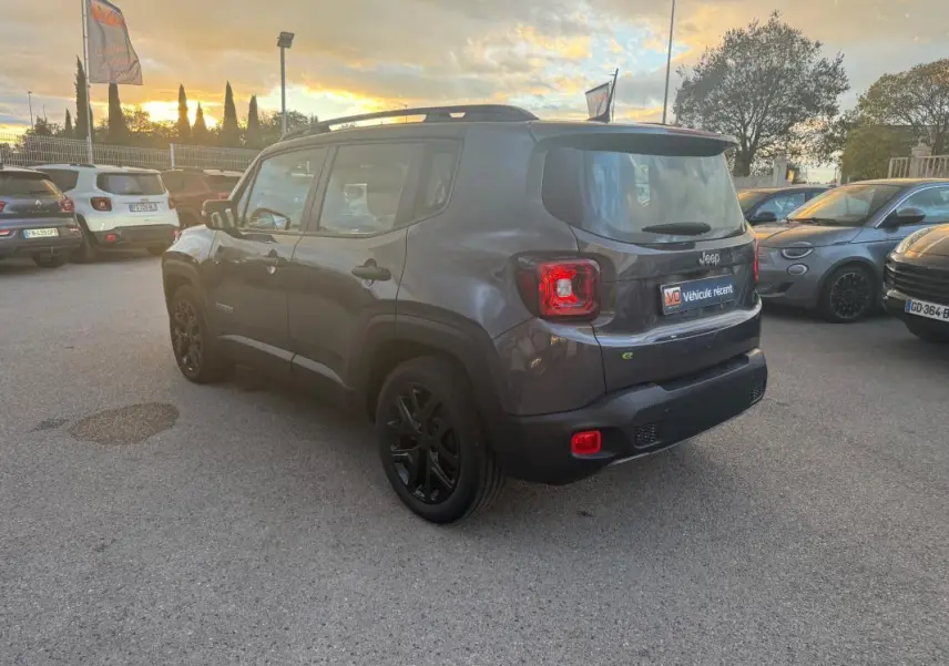 Jeep Renegade gris anthracite vue 3/4 arrière droit, avec barres de toit et jantes alliage noires de 18 pouces.