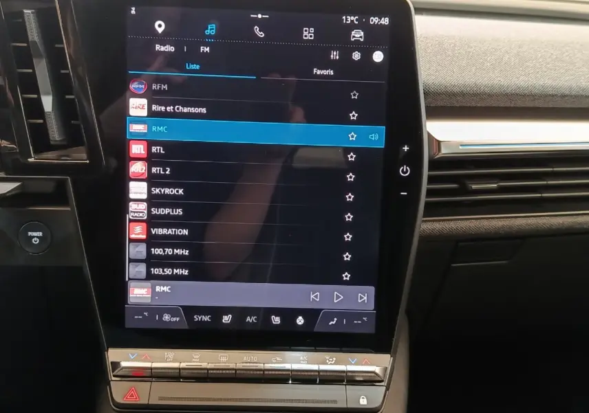 Vue rapprochée de l’écran tactile central de la Renault Mégane Techno EV60 220ch bleu, affichant les options radio et climatisation.