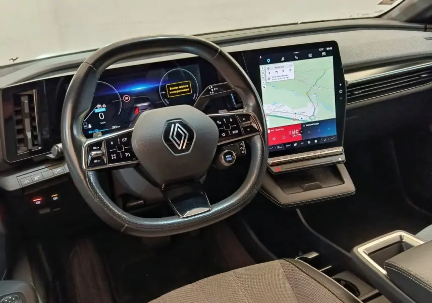Intérieur Renault Mégane Techno EV60 2023, vue tableau de bord avec volant cuir et grand écran tactile vertical.