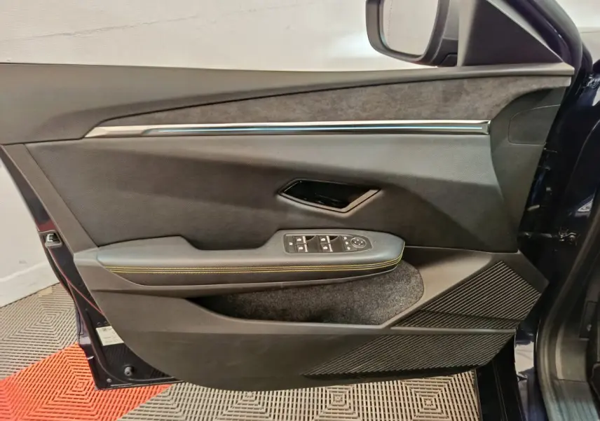 Vue côté intérieur de la porte avant gauche de la Renault Mégane Techno EV60 220ch bleu, avec commandes électriques et surpiqûres jaunes.