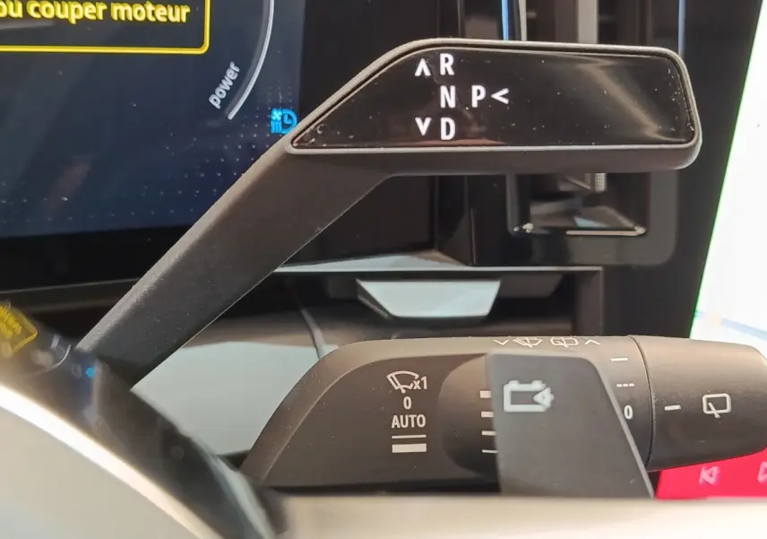Gros plan sur la commande de boîte automatique et les commandes d’essuie-glace du tableau de bord d’une Renault Mégane EV60 bleu.