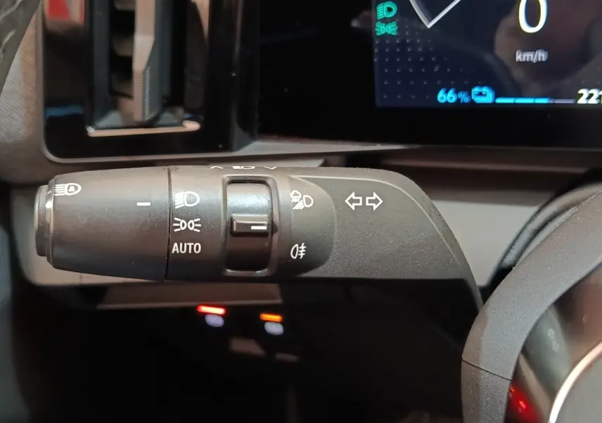 Gros plan sur la commande des feux et clignotants à gauche du volant dans le tableau de bord de la Renault Mégane bleu électrique 2023.