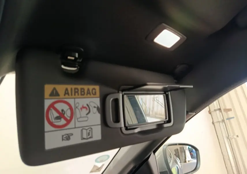 Miroir de courtoisie ouvert sur pare-soleil côté conducteur d'une Renault Mégane bleu, intérieur éclairé.
