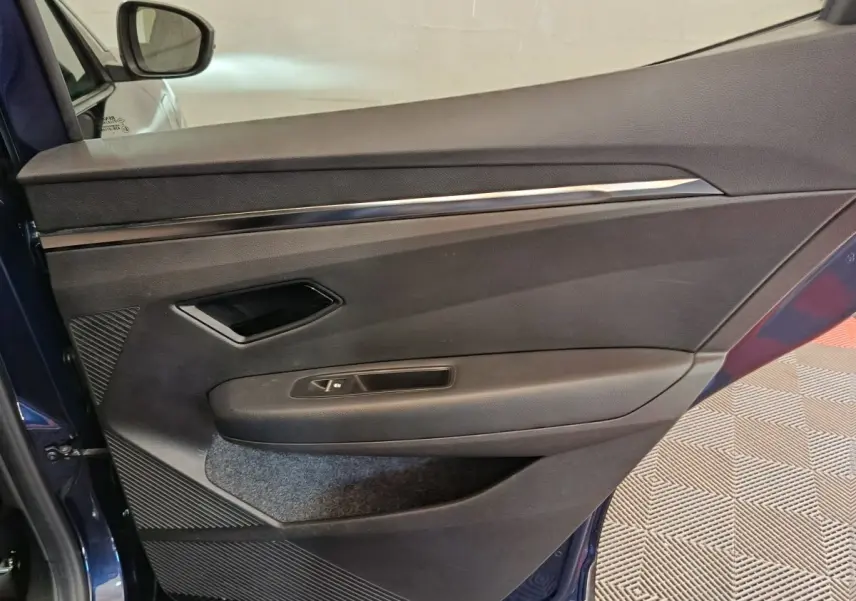 Intérieur de la porte côté gauche de la Renault Megane Techno EV60 bleu, avec poignée et commande de fenêtre.