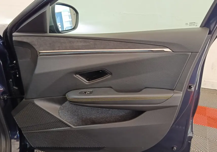 Vue intérieure de la porte avant gauche bleu foncé de la Renault Mégane 2023 avec surpiqûres jaunes et insert tissu.