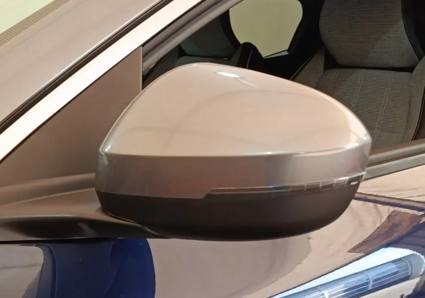 Rétroviseur côté conducteur gris sur Renault Mégane Techno EV60 bleu, vue rapprochée avec siège arrière visible.