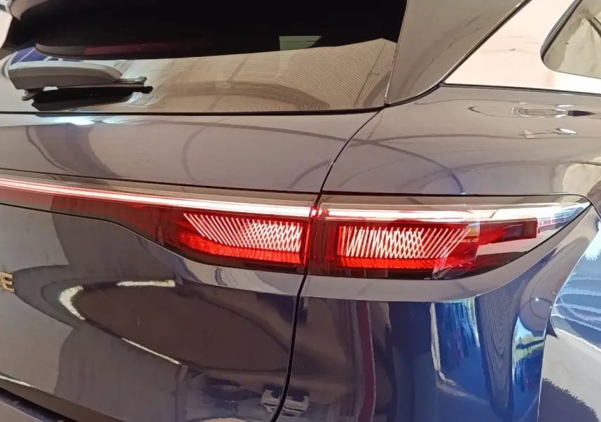 Feu arrière droit allumé sur Renault Mégane Techno EV60 bleu, vue rapprochée du côté arrière du véhicule.