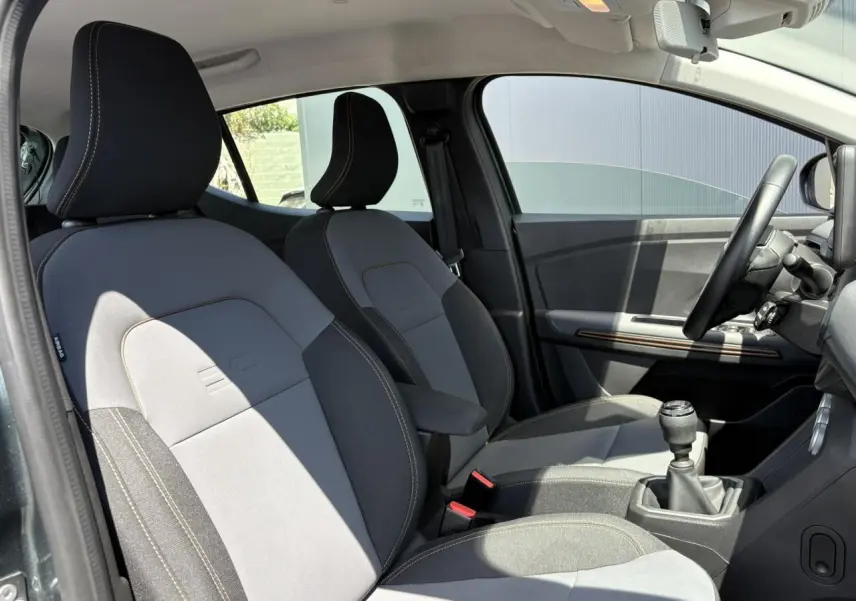 Vue intérieure côté conducteur de la Dacia Sandero Stepway 2025 avec sièges gris et accoudoir central.