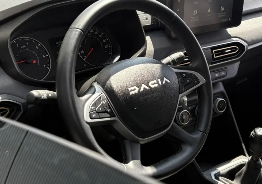 Vue rapprochée du volant noir Dacia et du tableau de bord avec écran tactile dans l’habitacle de la Sandero Stepway 2025.